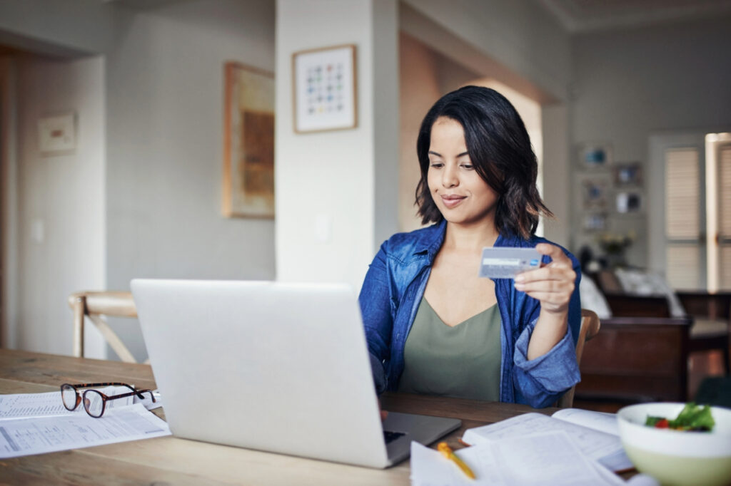 Electronic Bill Presentment and Payment - A woman at home using her laptop and credit card to pay for her medical bills.