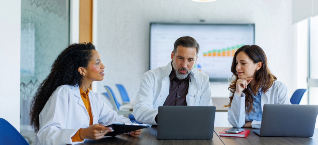 Revenue cycle management companies - Three doctors using laptops to check their practice’s analytics and reporting.