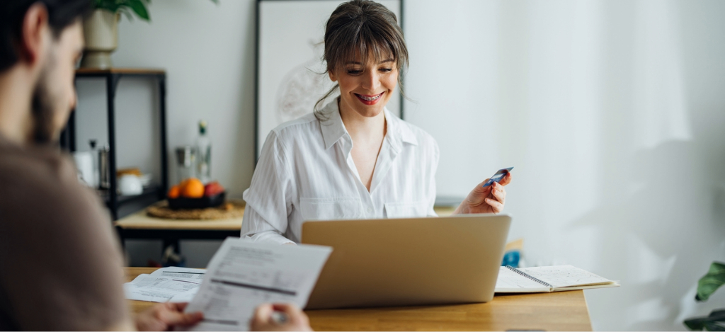 Private practice billing - A couple at home reviewing their medical bill and using a laptop and a credit card to pay online.