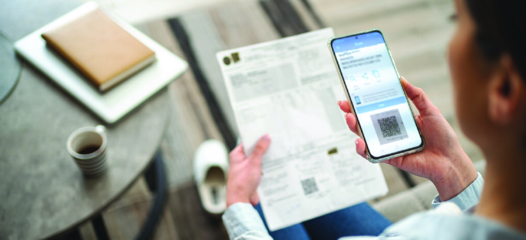 Managing delayed payments from patients - A woman using a smartphone to scan a QR code on her medical bill.