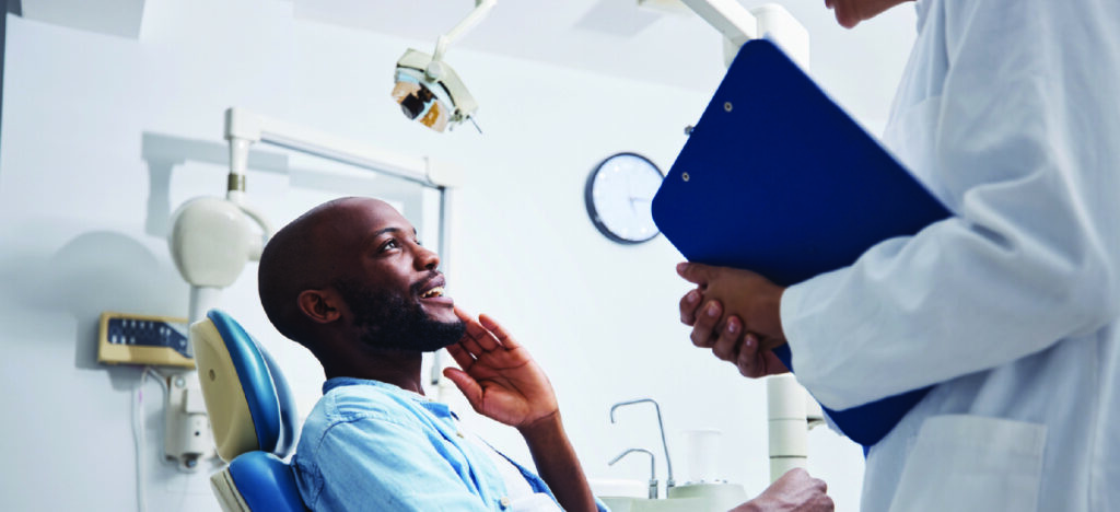 Offering dental patient financing - A male patient telling his dentist about his dental care problems.