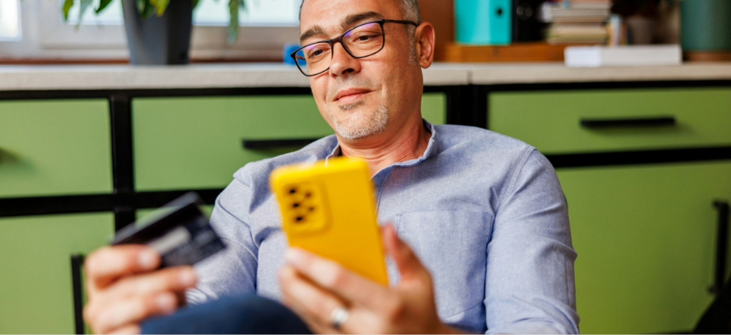 EHR integration - A man at home paying for his medical bill online using his smartphone and credit card.