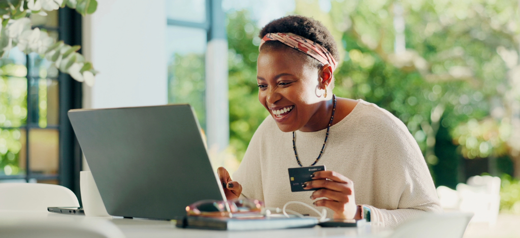 Dental software - A happy woman at home holding a credit card while paying for her dental bills online.