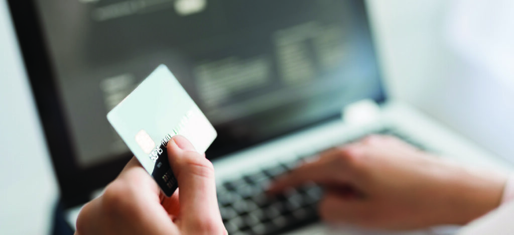  Automated reminders for patient payments - A woman holding her credit card while paying for her medical bills online.