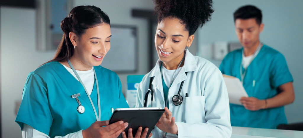 Reducing patient cancellations - Two female doctors checking patient appointment schedules using a tablet device.