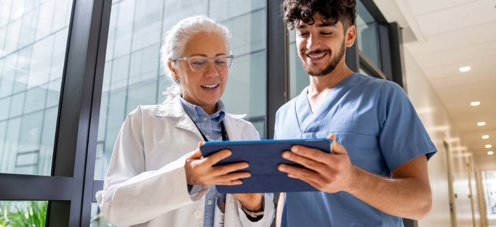 Automated patient billing - A female doctor and a male hospital staff member looking at a billing platform using a tablet device.