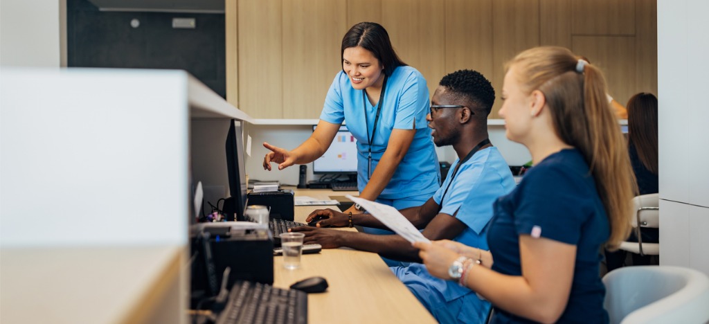 Automation for reducing administrative burden - A group of medical professionals using a computer while discussing administrative tasks.