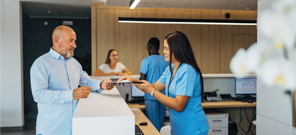 Improving revenue cycle - A female medical professional assisting a male patient in paying his hospital bills.