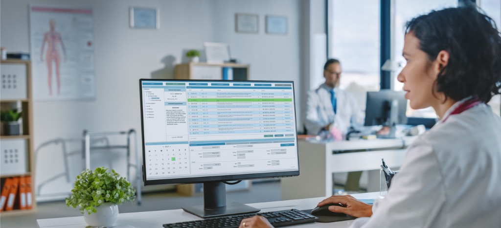 Reducing administrative burden - A female doctor using a computer to send automated billing reminders to her patients.