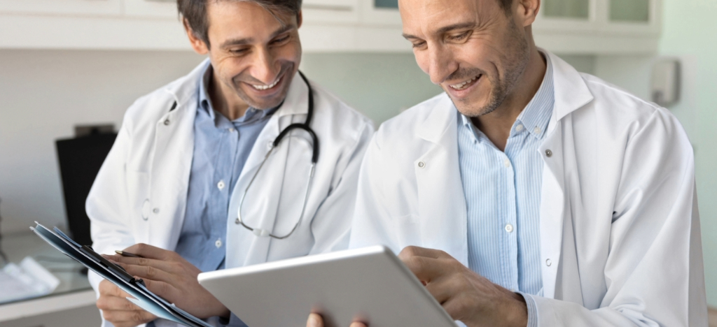 Using EBPP - Two male doctors using a tablet device to review their practice’s revenue.