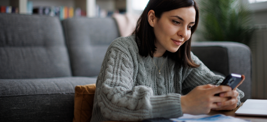Text to Pay - A woman at home using her smartphone to settle her online medical bill.