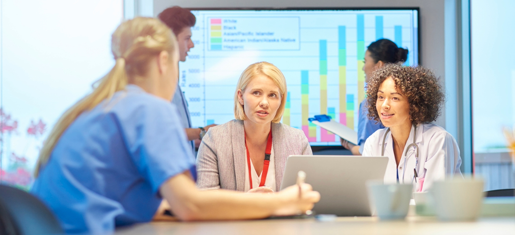 What is RCM - A businesswoman and a team of medical professionals discussing their practice’s revenue cycle.