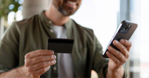 HIPAA-compliant text messaging - A man using his credit card and smartphone to pay for his medical bill.