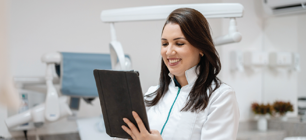 Dental billing software benefits - A female dentist using a tablet device to manage patient billing.