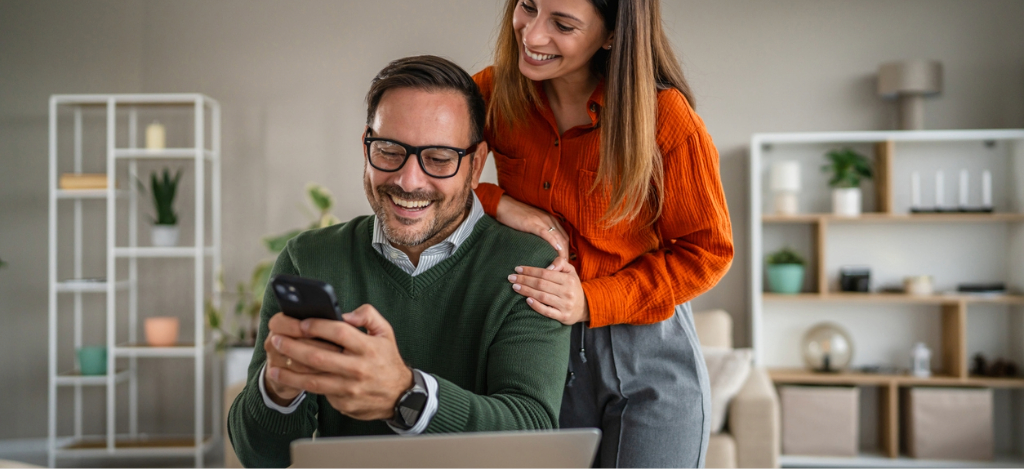 Self-payment for patients - A couple at home viewing their medical bill reminder using a laptop and a smartphone.