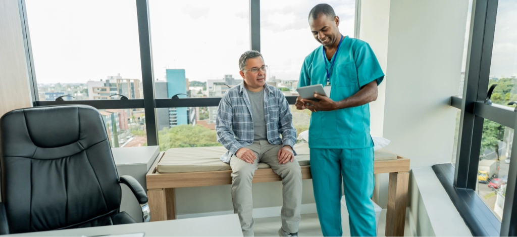 Electronic billing - A male doctor using a tablet device to verify his senior male patient’s contact information.